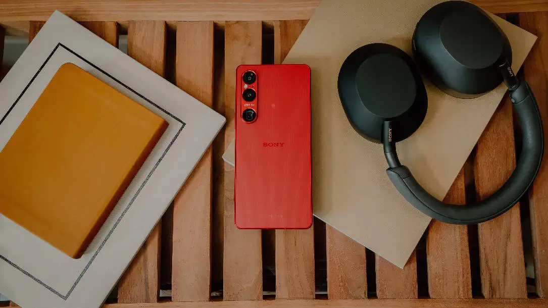 Un téléphone portable rouge et des écouteurs sur une surface en bois Description générée automatiquement